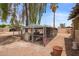Outdoor dog kennel on a gravel lot, partially shaded by mature trees, with a view of the property's exterior at 4922 W Fallen Leaf Ln, Glendale, AZ 85310