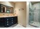 Well-lit bathroom with a black painted vanity, tile countertop, and a glass-enclosed shower with stone tile at 6102 E Sage Dr, Paradise Valley, AZ 85253
