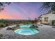 Inviting backyard pool and jacuzzi with rock features and panoramic views at dusk at 6102 E Sage Dr, Paradise Valley, AZ 85253