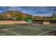 View of a well-maintained tennis court with a shaded seating area and mountain views at 7291 E Eagle Feather Rd, Scottsdale, AZ 85266