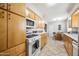 Functional kitchen featuring oak cabinets, white appliances, tile countertops, and an adjacent eat-in breakfast nook at 7307 N 17Th Ave, Phoenix, AZ 85021