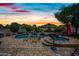 Stunning backyard featuring a sparkling pool, spa, lounge chairs, and lush landscaping under a vibrant sunset sky at 7342 E Norwood St, Mesa, AZ 85207