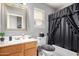 A cozy bathroom featuring a vanity with framed mirror, toilet, and a shower with a black shower curtain at 7460 E Kiowa Ave, Mesa, AZ 85209