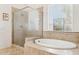 Bright bathroom featuring frosted glass shower, separate tub, and decorative tiled accents at 7587 W Quail Ave, Glendale, AZ 85308