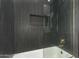Modern bathroom featuring black textured tile and a sleek glass-enclosed shower with gold hardware at 13367 W Jesse Red Dr, Peoria, AZ 85383