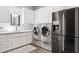 Laundry area with stainless steel appliances, white cabinetry, and a utility sink at 13750 E Yucca St, Scottsdale, AZ 85259