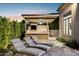 Outdoor kitchen includes lounge chairs, lush landscaping, a television, and a ceiling fan at 13750 E Yucca St, Scottsdale, AZ 85259