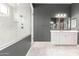This contemporary bathroom is designed with a sleek vanity, frameless shower, and tile floors at 13850 W Weaver Ct, Litchfield Park, AZ 85340