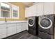 Modern laundry room with washer, dryer, and white cabinetry at 13850 W Weaver Ct, Litchfield Park, AZ 85340
