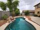Backyard with freeform pool featuring mature trees and rock feature at 13921 W Port Royale Ln, Surprise, AZ 85379