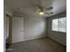 A view of a carpeted bedroom with a ceiling fan and window at 13921 W Port Royale Ln, Surprise, AZ 85379