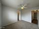 A view of a carpeted bedroom with a ceiling fan, entry and closet doors at 13921 W Port Royale Ln, Surprise, AZ 85379