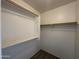 A walk-in closet with a carpeted floor and white shelving and clothing bars at 13921 W Port Royale Ln, Surprise, AZ 85379