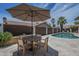 Outdoor dining area with umbrella seating next to a sparkling pool and serene landscaping at 1461 W Tara Dr, Gilbert, AZ 85233
