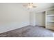Neutral bedroom with carpet, a ceiling fan, and custom built-in shelving at 14881 W Ashland Ave, Goodyear, AZ 85395