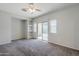 Bedroom featuring plush carpet, a ceiling fan, built-in shelves, and access to the backyard at 14881 W Ashland Ave, Goodyear, AZ 85395