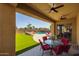 Covered back patio with fan, table, chairs, and a view of the pool and green lawn at 16206 W Cocopah St, Goodyear, AZ 85338