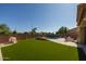 Large backyard featuring artificial turf, a swimming pool with waterfall, and surrounding homes at 16206 W Cocopah St, Goodyear, AZ 85338