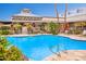 Bright and refreshing community pool with clear blue water, set amongst a landscaped deck with tables, chairs, and greenery at 17651 N Coconino Dr, Surprise, AZ 85374