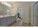 Bright bathroom featuring double vanity sinks, modern fixtures, and an open doorway to the main bedroom at 17969 W Sand Hills Rd, Surprise, AZ 85387