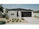 Charming single-story home featuring a gray stucco finish, a black garage door, and desert landscaping at 17969 W Sand Hills Rd, Surprise, AZ 85387