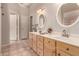 Bathroom showcasing double sinks, wood cabinets, tiled floors, and decorative mirrors at 1811 S Brentwood Pl, Chandler, AZ 85286