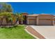 Charming single-story home with a three-car garage, lush green lawn, and desert landscaping at 1811 S Brentwood Pl, Chandler, AZ 85286