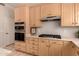 Well-equipped kitchen boasts wood cabinetry, double ovens, and a gas cooktop at 1811 S Brentwood Pl, Chandler, AZ 85286