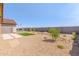 Wide view of the backyard with desert landscaping and a small square green lawn area at 18244 W Soft Wind Dr, Surprise, AZ 85387