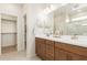 Bathroom with double sinks, wood cabinets, walk-in closet and a glass enclosed shower at 18244 W Soft Wind Dr, Surprise, AZ 85387