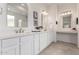 Double vanity bathroom featuring white cabinets, framed mirrors, and accent lights at 18453 W Elwood St, Goodyear, AZ 85338
