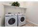 Well-lit laundry room with front loading washer and dryer and shelving at 18453 W Elwood St, Goodyear, AZ 85338