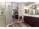 Bathroom with dual sinks, vanity, framed mirrors, glass shower, and tile floor at 18653 W Mescal St, Surprise, AZ 85388