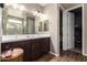 Bathroom with dual sinks, vanity, framed mirrors, and access to a walk-in closet at 18653 W Mescal St, Surprise, AZ 85388