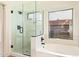 Bathroom showcasing a walk-in shower with glass door, a soaking tub, and a window providing natural light at 2027 S Rowen St, Mesa, AZ 85209