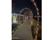 A view of a sidewalk covered with decorated illuminated archways with homes in the distance at 20421 W Legend Trl, Buckeye, AZ 85396