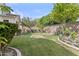 A lush backyard featuring manicured lawn, flowering trees, and mature landscaping at 211 W New Dawn Dr, Chandler, AZ 85248