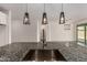 Close up of a kitchen island, granite counter top, stainless steel sink and modern pendant lighting at 22568 E Rosa Rd, Queen Creek, AZ 85142