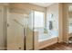 Bright bathroom featuring a glass-enclosed shower, soaking tub, and a large mirror for a luxurious feel at 28136 N 90Th Ln, Peoria, AZ 85383