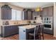Bright kitchen with gray cabinets, stainless appliances, quartz counters, tile backsplash, and island seating at 28136 N 90Th Ln, Peoria, AZ 85383