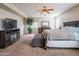 A spacious primary bedroom with cozy decor, a ceiling fan, and a TV stand with fireplace at 28136 N 90Th Ln, Peoria, AZ 85383