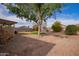 A spacious backyard with a covered patio, gravel, sparse grass, mature trees and block wall fencing at 40427 N Orkney Way, San Tan Valley, AZ 85140