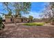 A spacious backyard with a covered patio, gravel, grass, mature trees and block wall fencing at 40427 N Orkney Way, San Tan Valley, AZ 85140