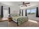 Sunlit main bedroom with a floral-patterned bed, ceiling fan, and large windows, creating a calming retreat at 4771 E Meadow Land Dr, San Tan Valley, AZ 85140