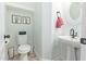 Cozy powder room with a pedestal sink, charming cactus artwork, and a modern toilet paper holder at 4771 E Meadow Land Dr, San Tan Valley, AZ 85140