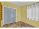 A simple bedroom with tile-look flooring, a closet with blue doors, and a window, providing a bright and functional living space at 701 S 92Nd St, Mesa, AZ 85208