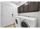 Convenient laundry room with tiled flooring, a modern washer and dryer, and storage cabinets at 7214 W Crest Ln, Glendale, AZ 85310