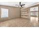 Spacious living room with neutral colors, ceiling fan, and built-in shelving at 7214 W Crest Ln, Glendale, AZ 85310