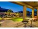 Inviting outdoor patio with a covered seating area, lush landscaping, a charming stone waterfall and an outdoor table at 7904 E Quill Ln, Scottsdale, AZ 85255