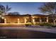 Stunning home featuring a three-car garage, stone accents, desert landscaping, and modern design at twilight at 7904 E Quill Ln, Scottsdale, AZ 85255